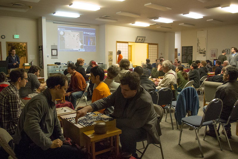 AlphaGo game being watched at Seattle Go Center, with table goban used in foreground